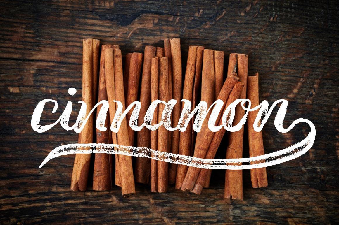 Pile of cinnamon sticks on dark rustic wood table with text overlayed